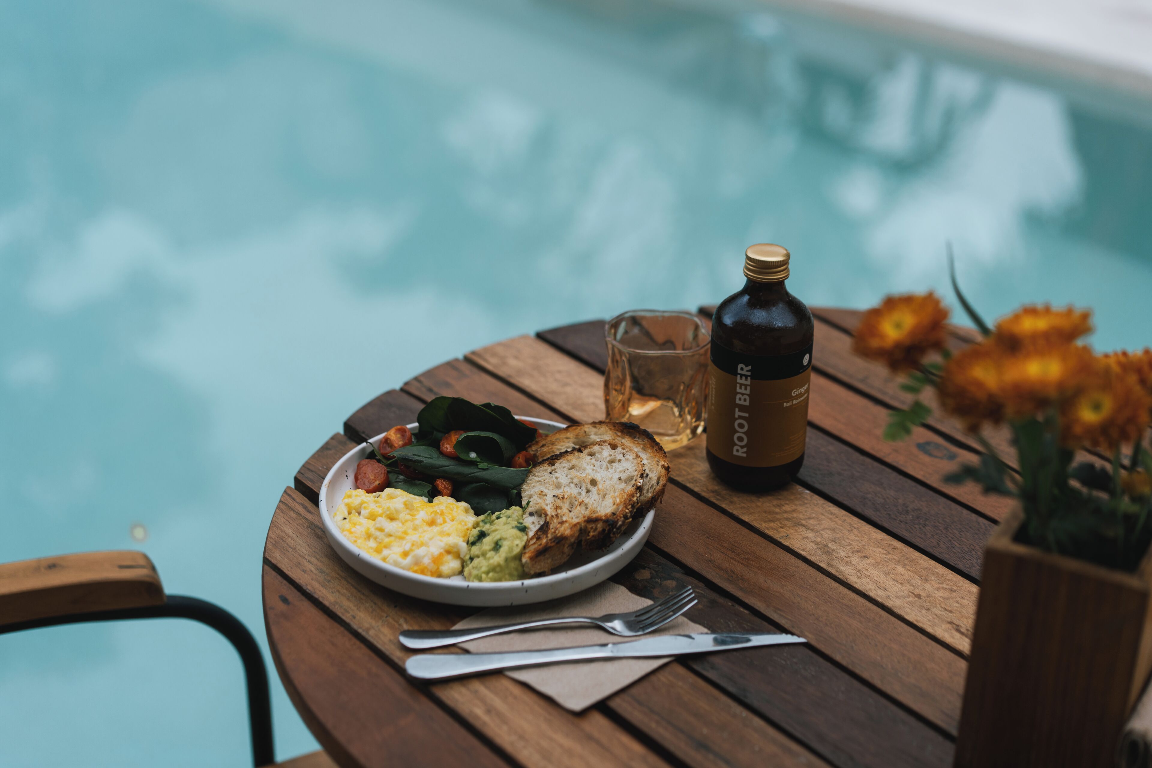 A wooden table with a plate of food, a bottle, and a glass.
