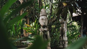 En stenhugget figur i frodigt, grønt landskab.