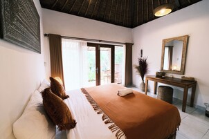 Un dormitorio con una cama grande, un escritorio, un espejo y vistas al exterior.