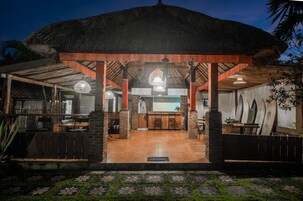 Un área de comedor al aire libre con techo de paja, pilares de ladrillo y una barra.