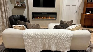 Una sala de estar con chimenea, un sofá, un televisor y una puerta.