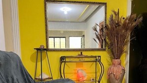 A room with a yellow wall, a large mirror, a fireplace, and a guitar. - Hostel Sideral (Campo Grande)