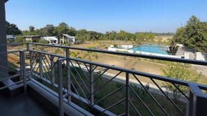 A view from a balcony overlooking a swimming pool, a grassy area, and a few buildings. - Foxtail Orchid (Bokakhat)