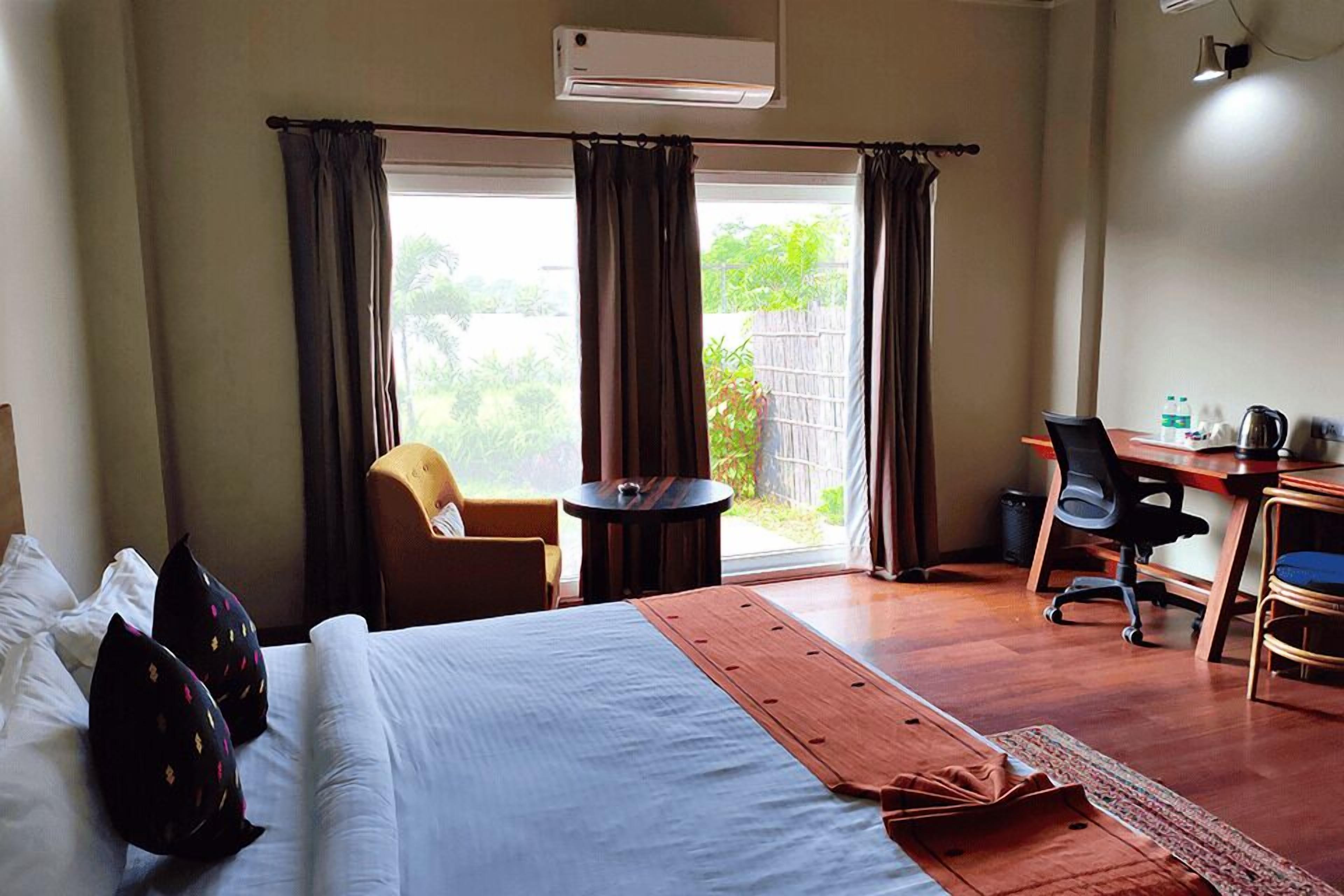 Habitación de hotel con cama, escritorio, silla y vista al exterior.