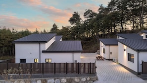 A modern building with a flat roof, a stone wall, and a wooden fence.