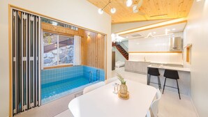 Uma cozinha moderna com armários brancos, uma área de refeições com mesa branca e uma piscina com azulejos azuis.