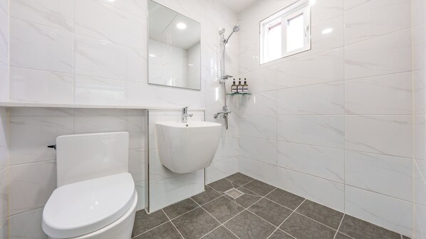 Une salle de bain moderne équipée de toilettes, d’un lavabo et d’une douche.