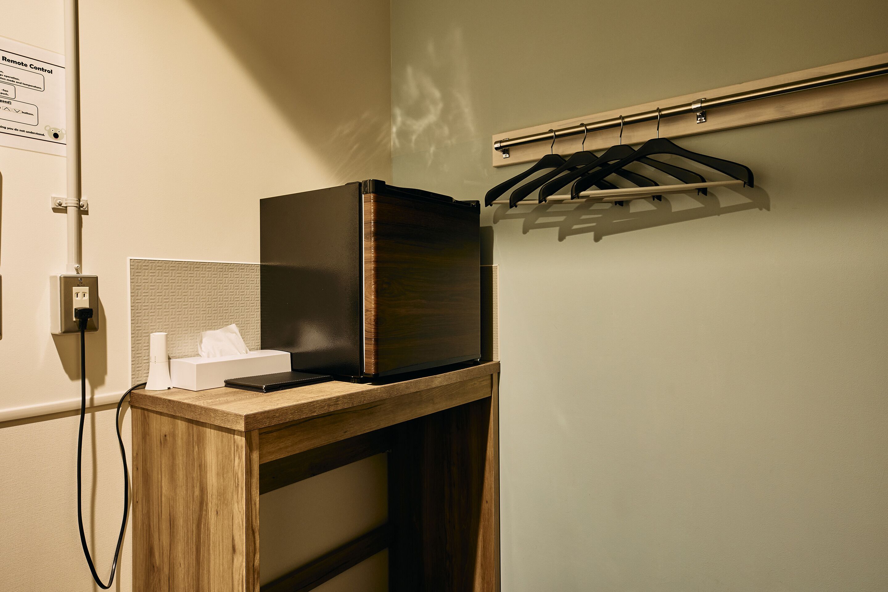 A wooden desk with a black electronic device, a tissue box, and a cable.