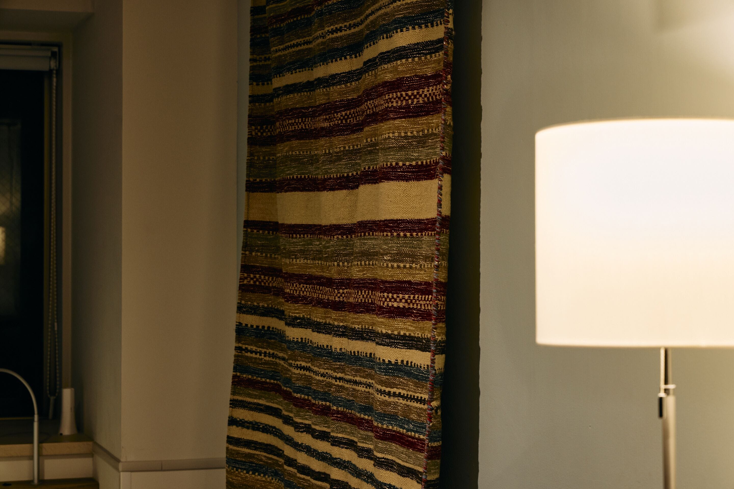 A patterned wall hanging and a lamp in a room.