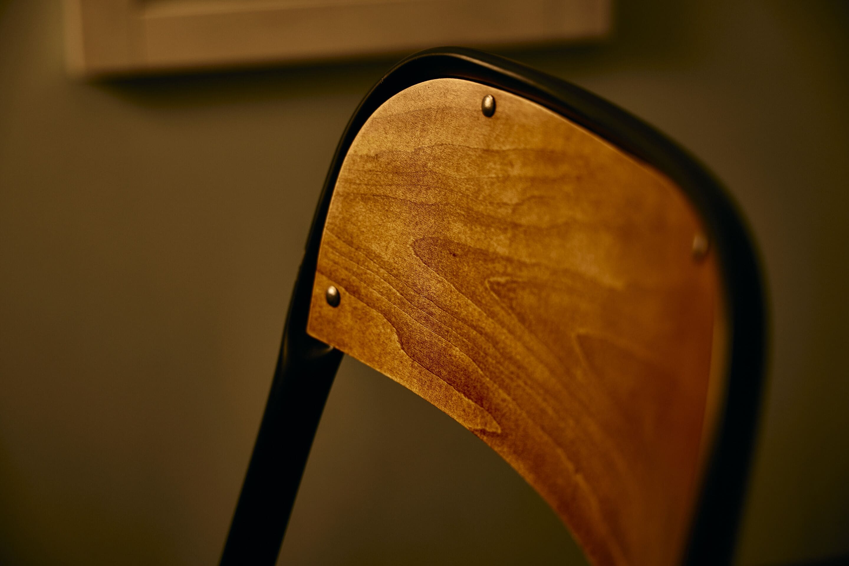 A close-up of a wooden chair with a black frame.