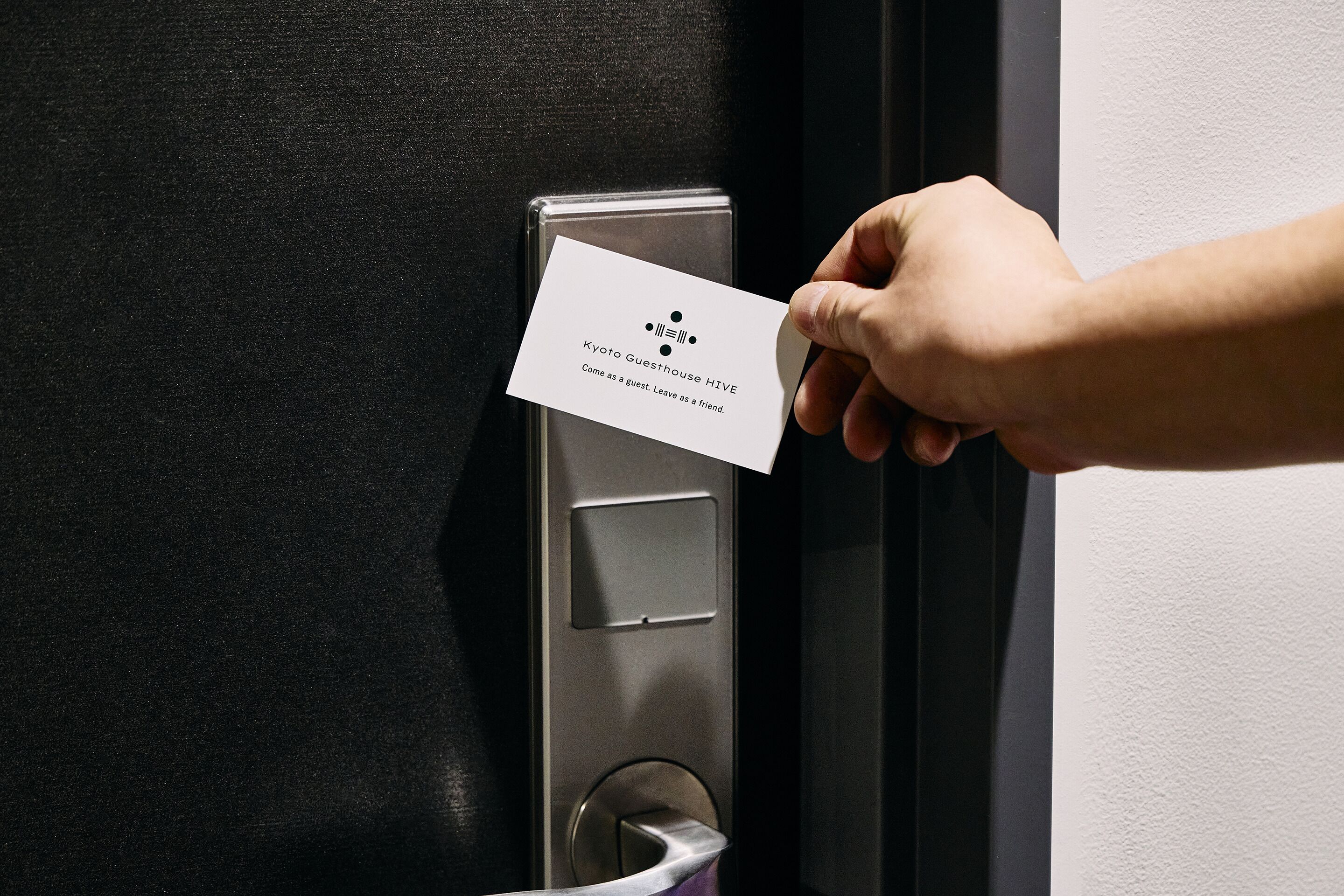 A hand inserting a card into a door lock mechanism.