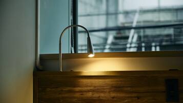 A wooden cabinet with a modern faucet and a window with a view of an industrial structure.