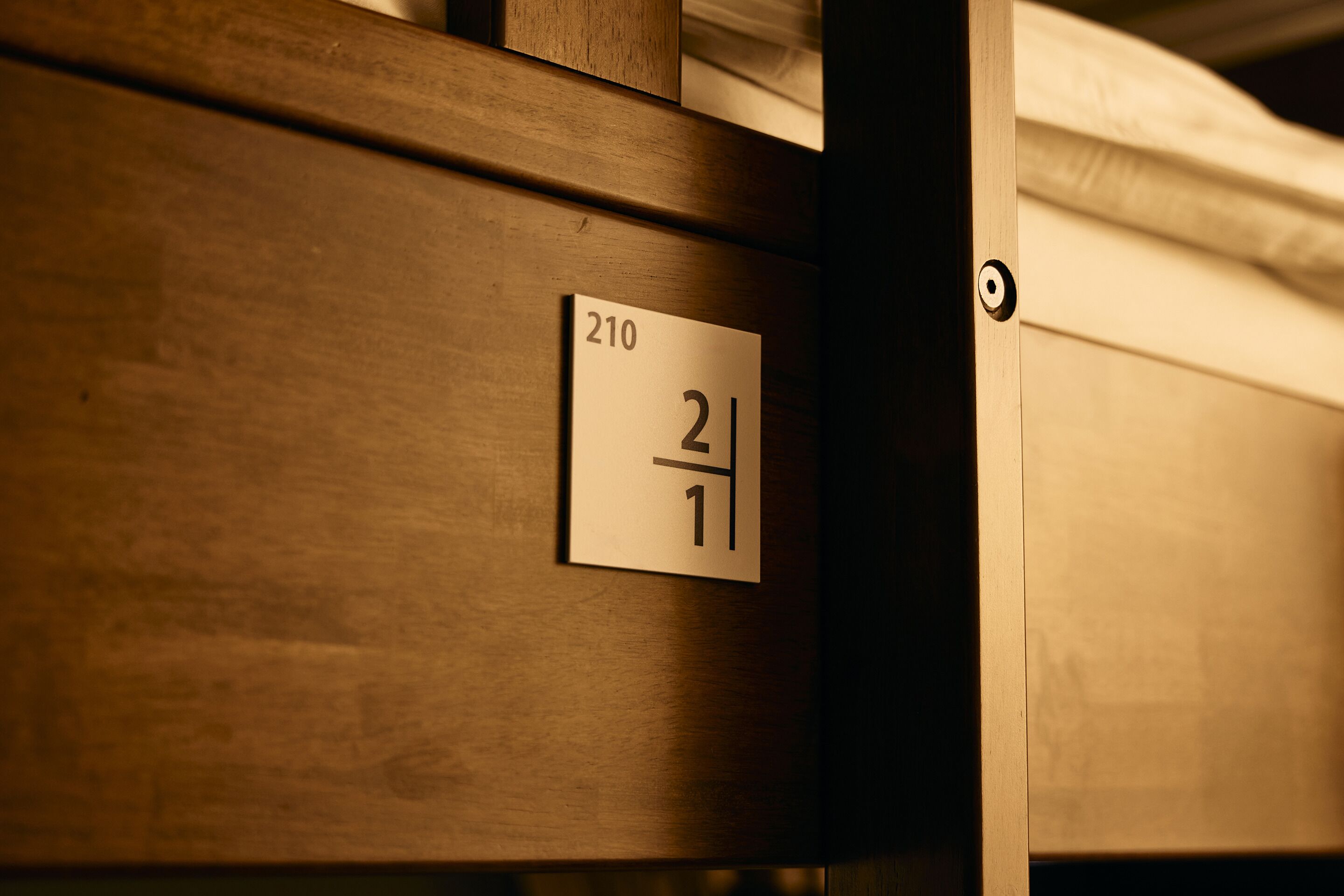 A wooden room with a sign indicating room number 210.