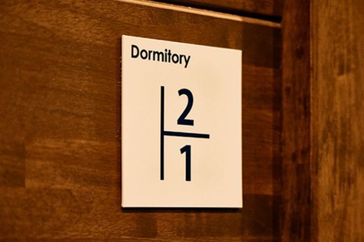 Une pancarte indiquant « Dortoir 2/1 » est fixée à un mur en bois.