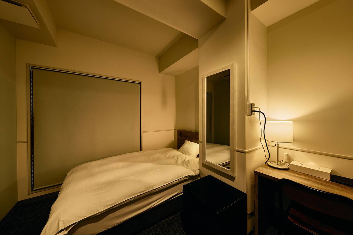 Ein Hotelzimmer mit Bett, Schreibtisch, Spiegel und Lampe.