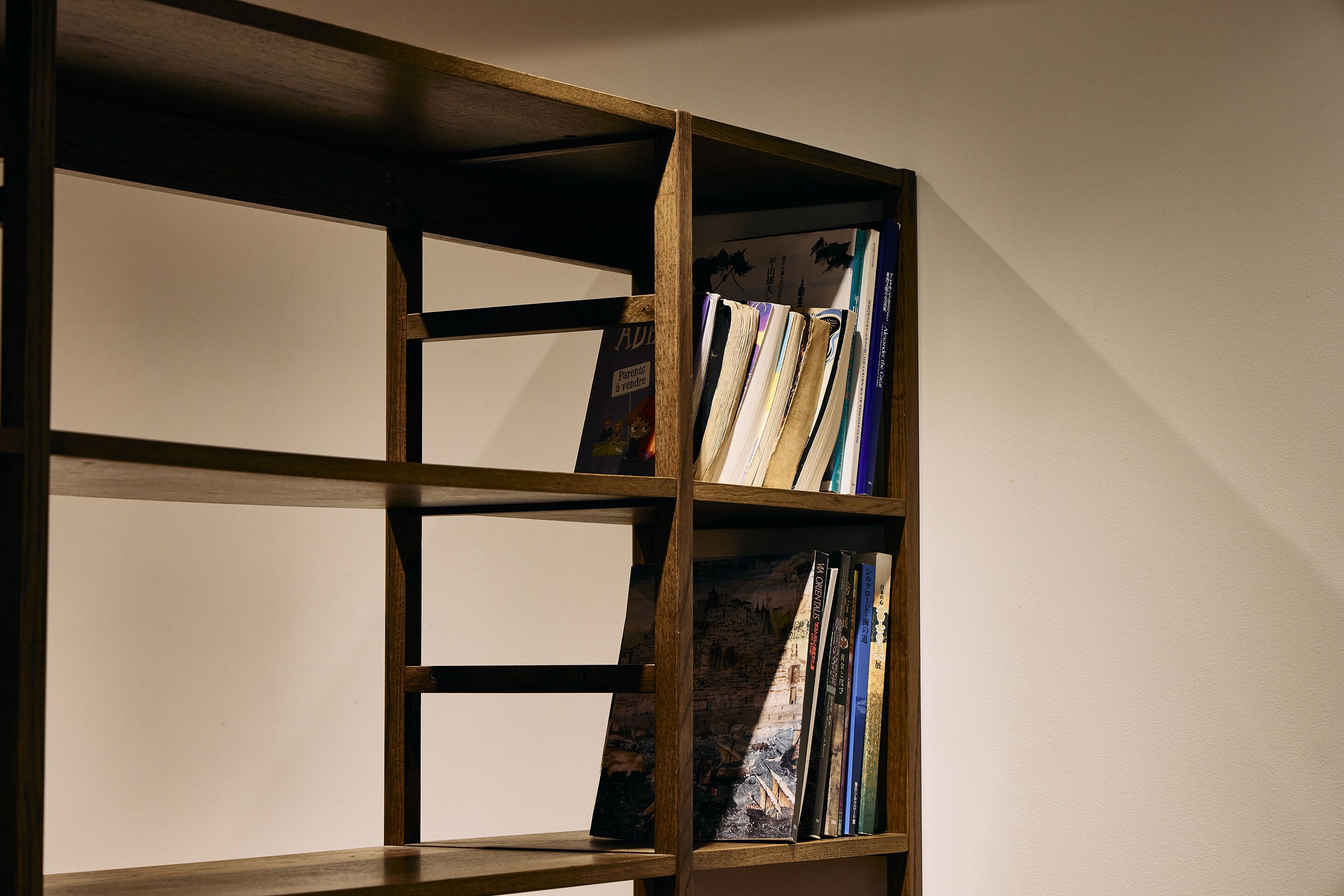 A wooden bookshelf with multiple compartments, some filled with books and others empty.