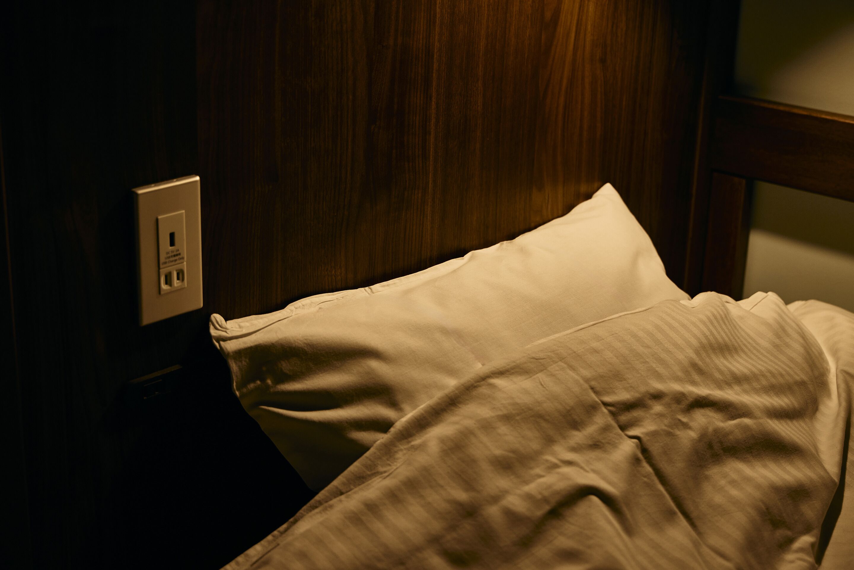 A bed with a white pillow and a wooden headboard.