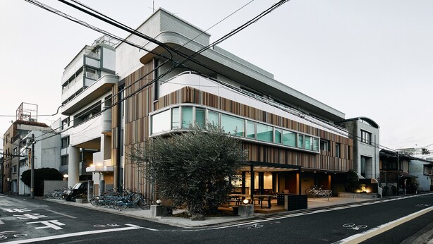 Un bâtiment moderne doté d’un espace extérieur couvert avec des sièges, d’un support à vélos et d’un chemin piétonnier.
