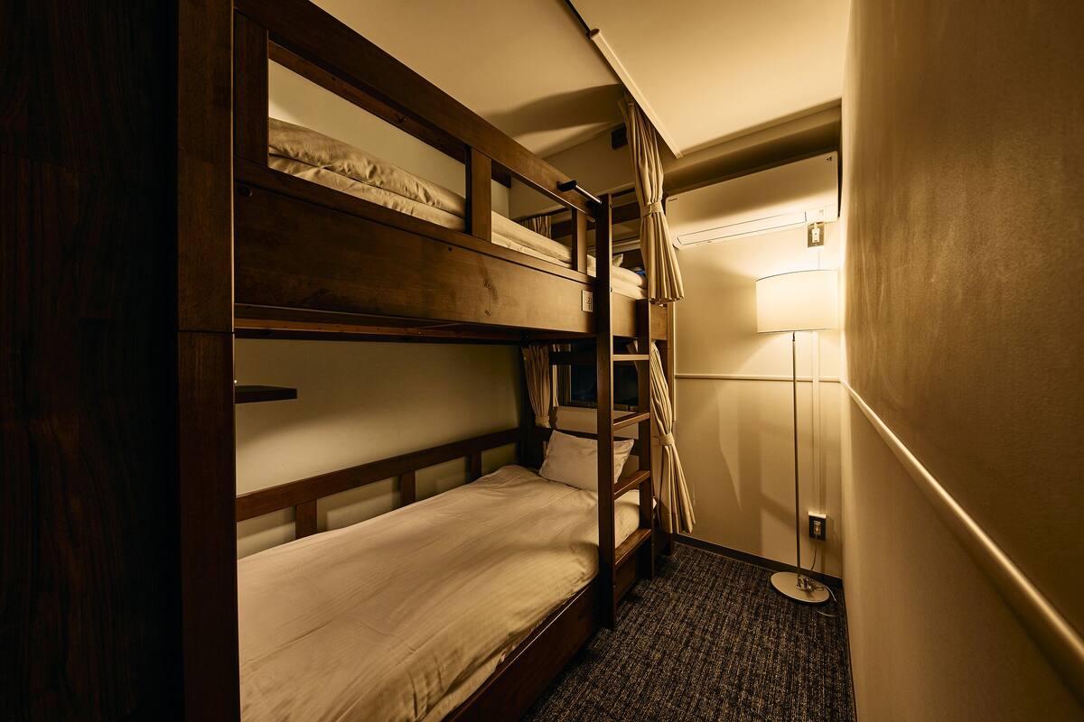 Ein Schlafzimmer mit Etagenbetten, einer Lampe und einer Steckdose an der Wand.