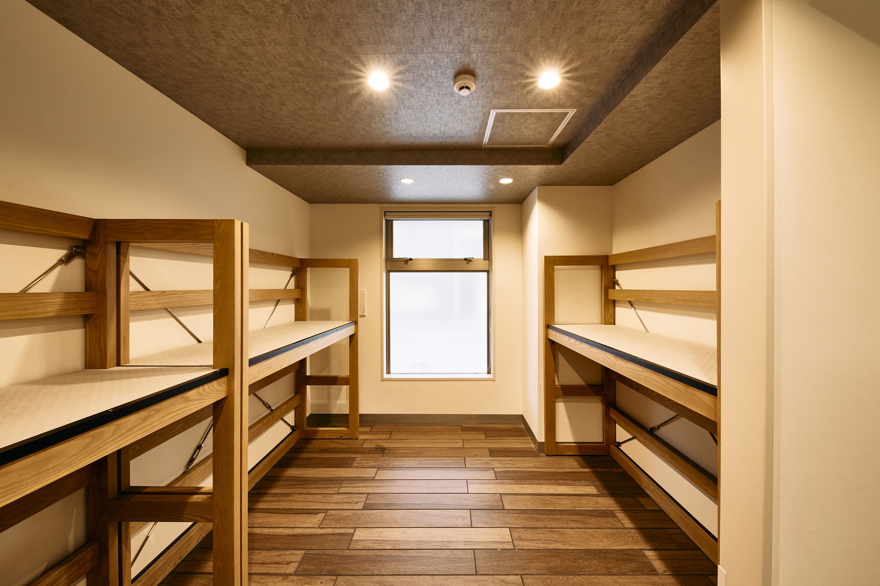 A room with bunk beds, a window, and a ceiling with recessed lighting.