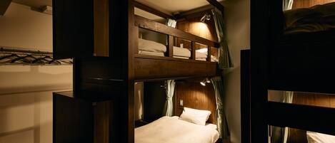 A bunk bed room with a wooden headboard, a bedside table, and a lamp.