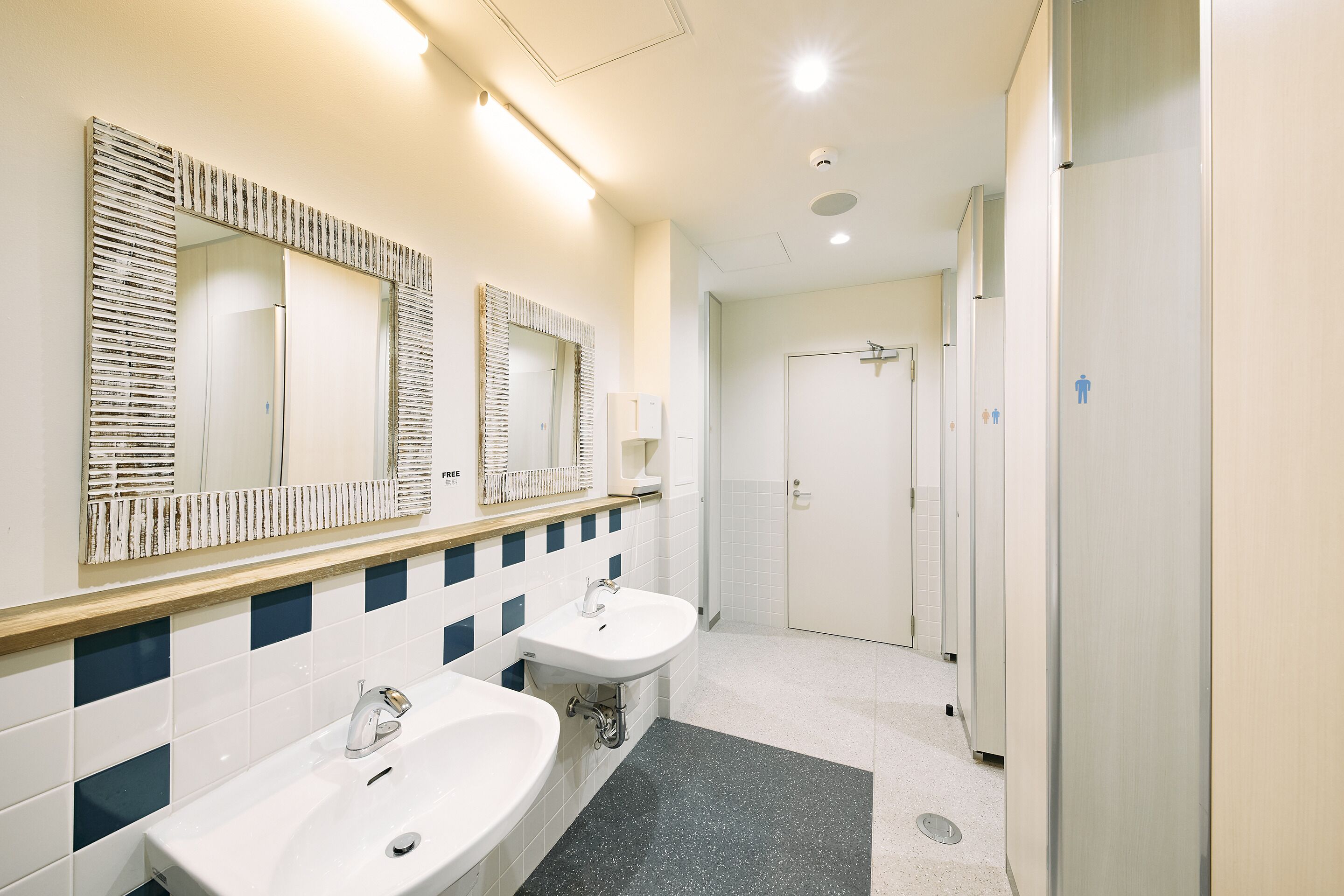 A modern bathroom with two sinks, large mirrors, and a shower area.