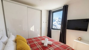 Un dormitorio con cama, ventana con vistas, televisión y armario.