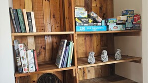 A wooden bookshelf with various books and games. - Villa of the Three Monkeys. Between the beach and the mountains. (Saint-Pierre)