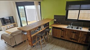A compact kitchen with a wooden bar, a sofa, and a TV. - Villa of the Three Monkeys. Between the beach and the mountains. (Saint-Pierre)