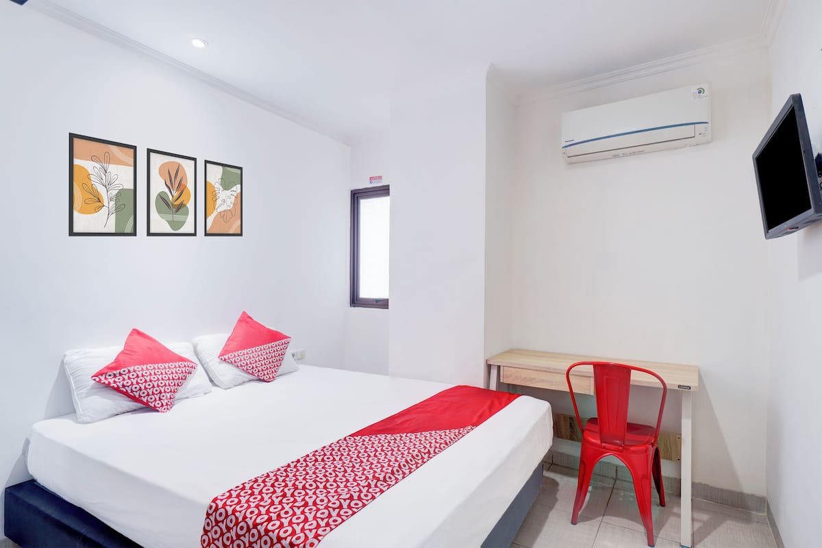 A hotel room with a bed, a desk, a chair, and a TV.