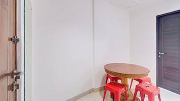 A small room with a round wooden table and four red stools.