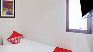 Una habitación con cama, ventana y un cuadro en la pared.
