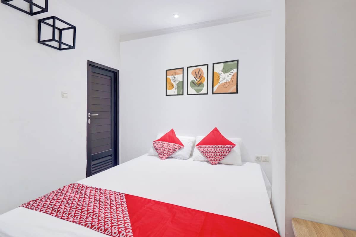 A hotel room with a bed, a door, and three wall-mounted pictures.
