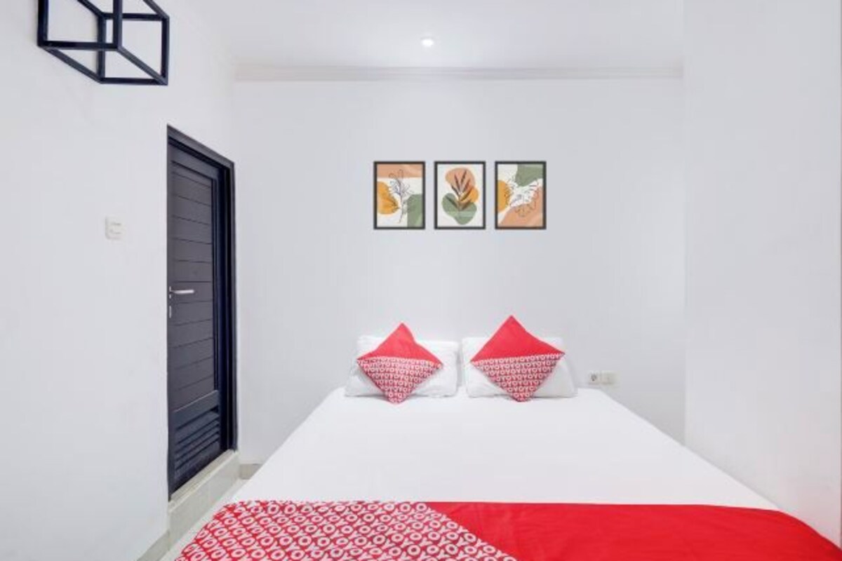 Un dormitorio con cama, una puerta y tres cuadros en la pared.