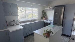 A modern kitchen with grey cabinets, a white island, and a stainless steel refrigerator.