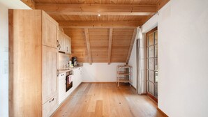 Eine Küche mit Holzausstattung, Holzboden und einem fenster mit Vorhängen.