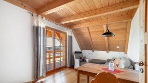 Ein Holzinterieur mit Esstisch, Stühlen, einer Couch und einer Deckenleuchte.
