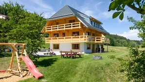 Ein großes Haus mit Balkon, Rutsche und Picknicktisch.
