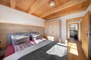A bedroom with a wooden ceiling, a bed with patterned bedding, and a wardrobe.