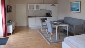 Un espace de vie compact comprenant un coin cuisine, un coin repas et un canapé.