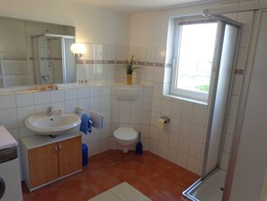 A bathroom with a sink, toilet, shower, and a window. - Apartment '3-Raum-Ferienwohnung' with Private Terrace, Shared Garden and Wi-Fi (Wesselburener Deichhausen)