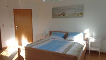 Ein Schlafzimmer mit einem hölzernen Bett, Nachttischen, einem an der Wand befestigten Kunstwerk und einer Tür.