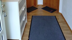 Un pasillo con puertas de madera, un armario blanco y un tapete negro en el suelo.