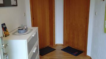 Ein Flur mit Holztüren, einem weißen Schrank und einer schwarzen Matte auf dem Boden.