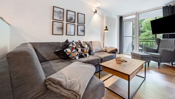 A modern living room with a grey sofa, a wooden coffee table, and a TV.