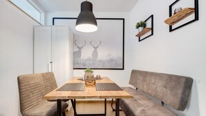 A dining area with a wooden table, cushioned chairs, a bench, a pendant light, and framed artwork on the wall.