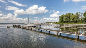 A calm marina with wooden docks and boats, surrounded by trees and a clear sky.