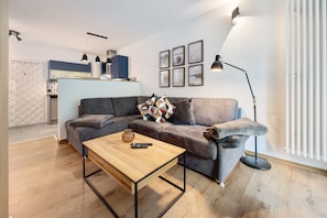 Un salon moderne avec un canapé gris, une table basse en bois et un lampadaire.