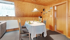 A wooden-paneled room with a round table set for dining, a radiator, and a window with a view. - Apartment 'Hecke' with Shared Garden and Wi-Fi (Weddingstedt)