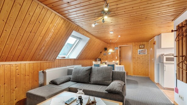 A cozy room with a wooden ceiling, a sofa, a small table with a ship model, and a window. - Apartment 'Hecke' with Shared Garden and Wi-Fi (Weddingstedt)